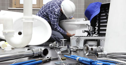 Plumber fixing toilet in bathroom